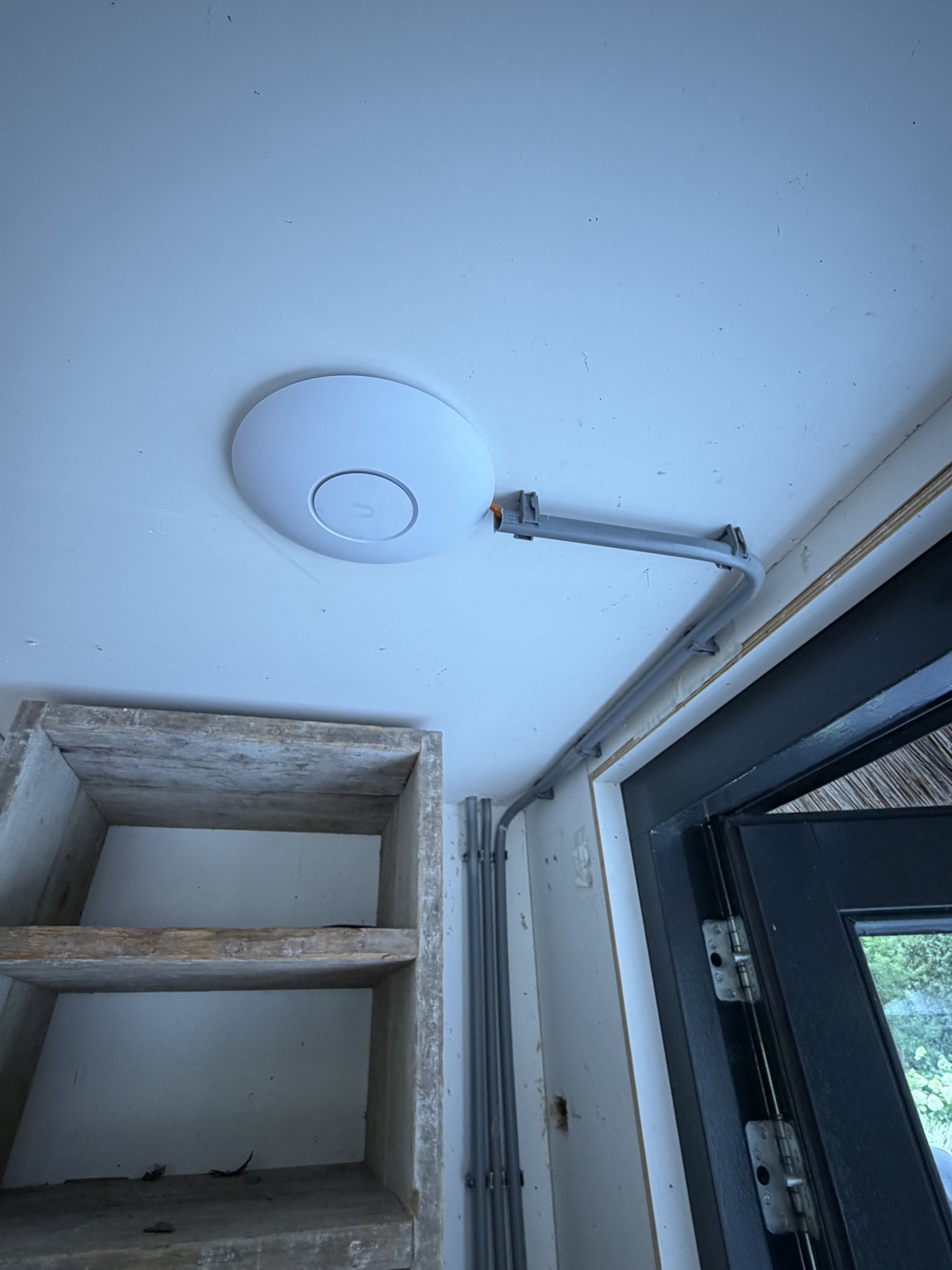 Wit accesspoint aan de wand van een bijgebouw met houten balken