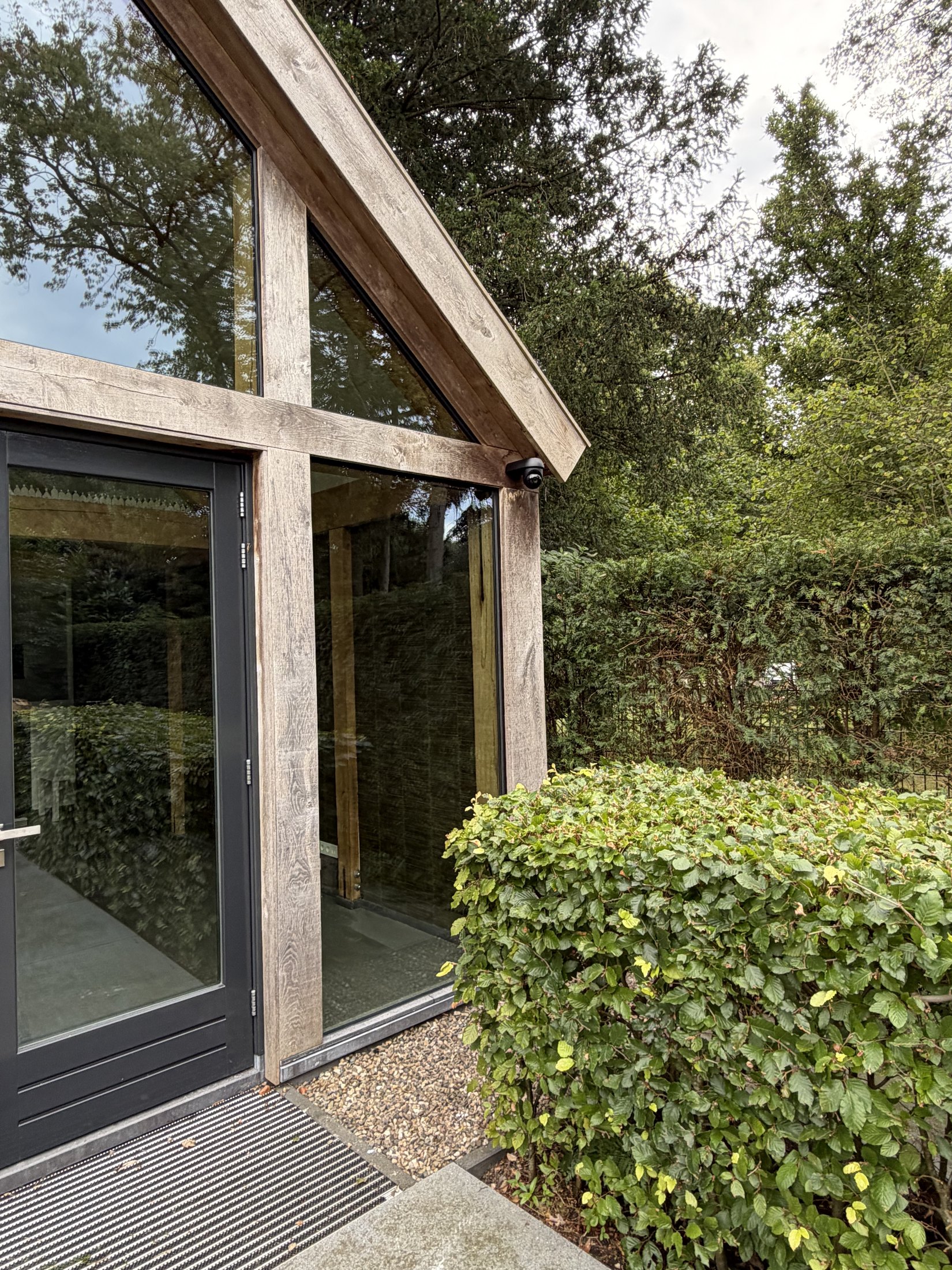 Kleine zwarte camera op de houten balk van een glazen orangerie