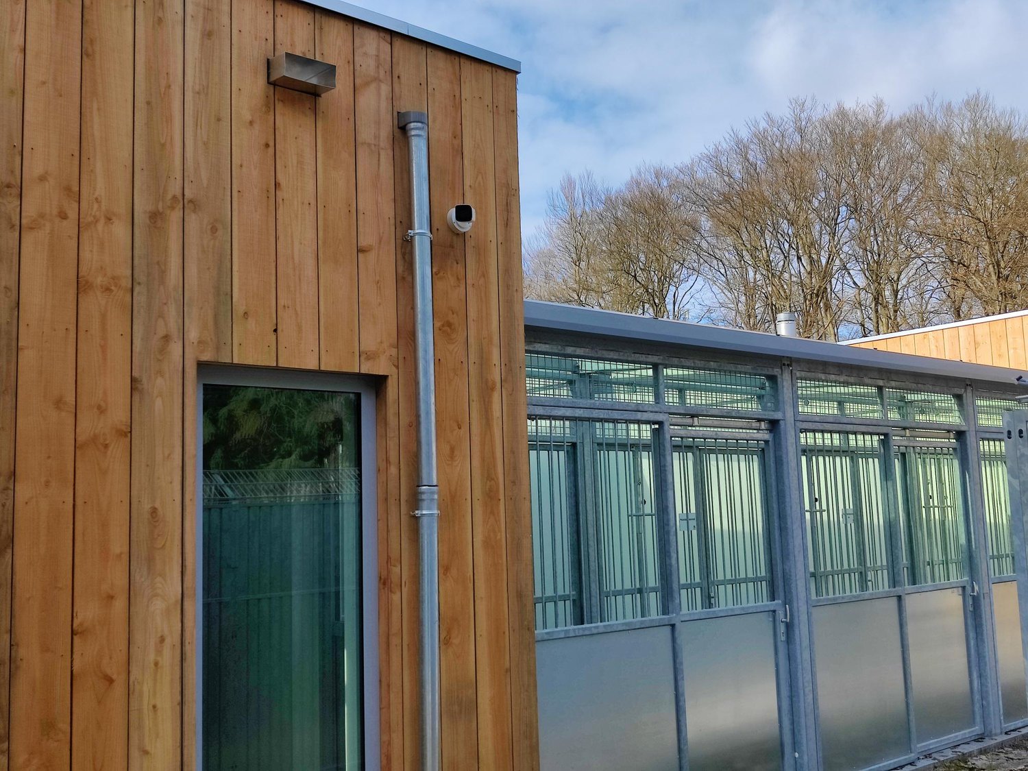Camera op een houten bijgebouw, in kleur afgestemd op het hout