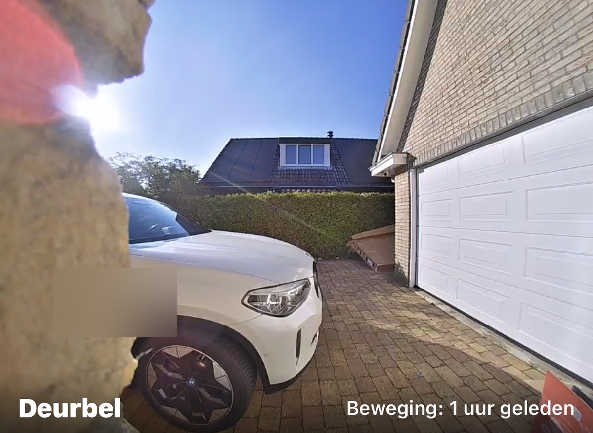 Beeld van een deurbelcamera met het label Deurbel: de eigen oprit met een witte auto en de garagedeur, kenteken onherkenbaar gemaakt