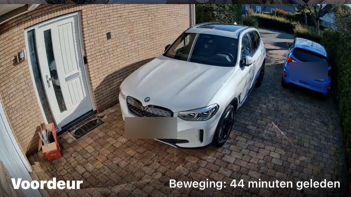Camerabeeld met het label Voordeur: de eigen voordeur en oprit met twee auto's, kentekens onherkenbaar gemaakt