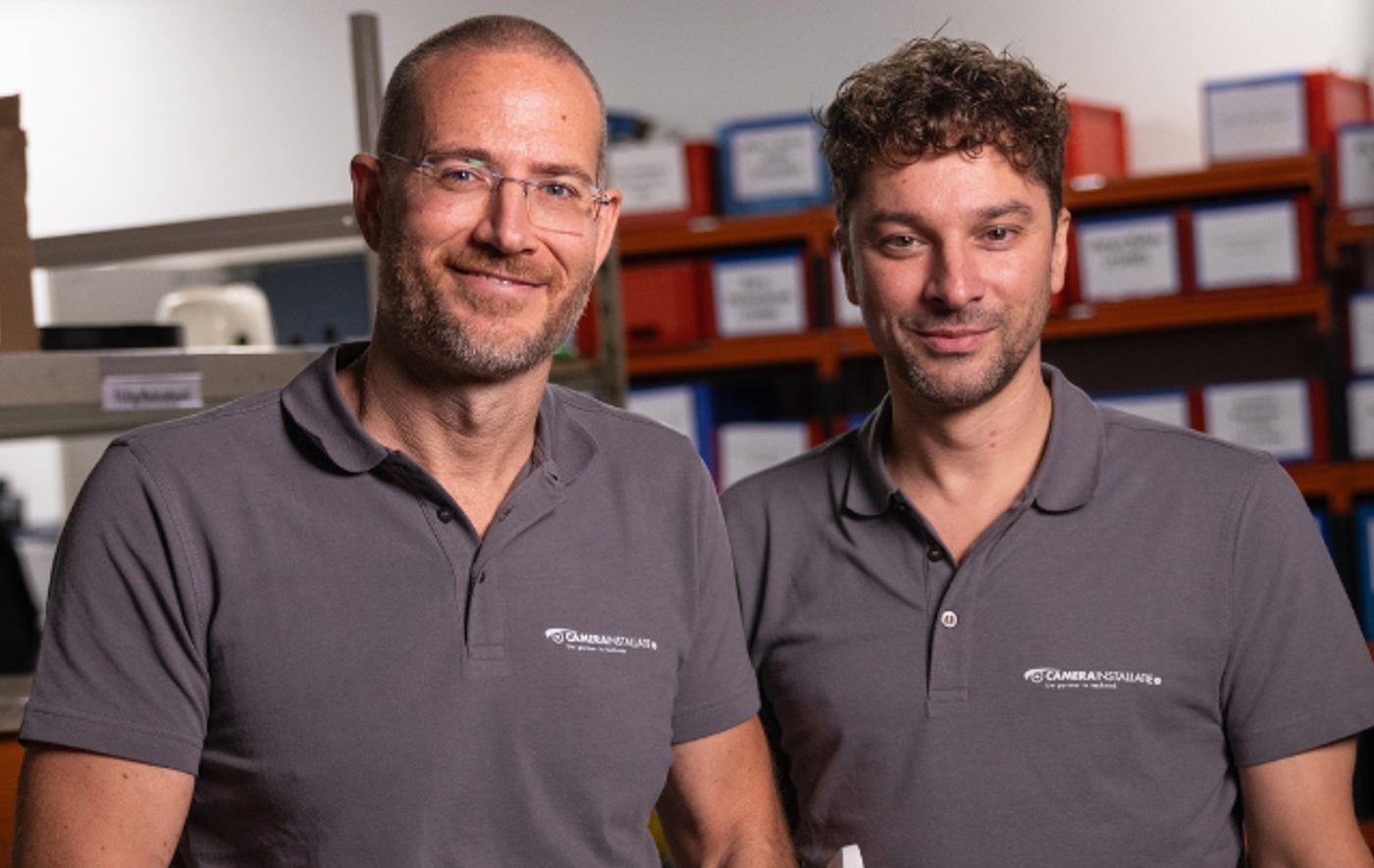 De twee oprichters naast elkaar in het magazijn, allebei in een grijze bedrijfspolo