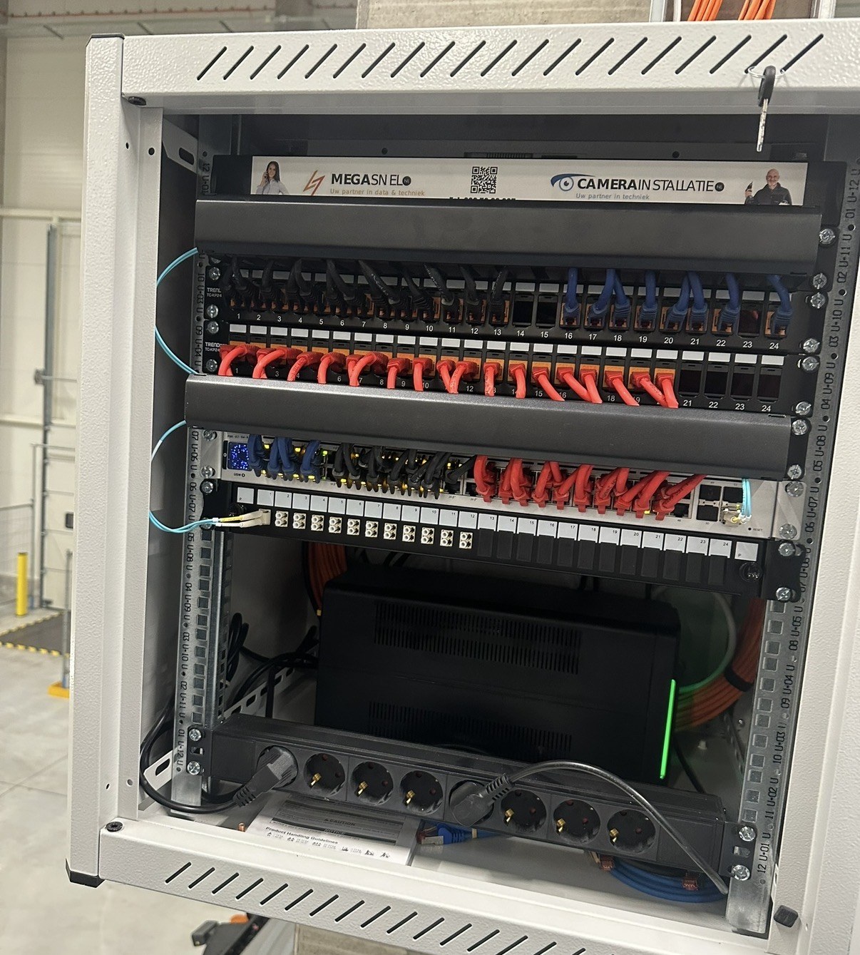 Nette patchkast met strak opgelegde kabels, genummerde poorten en het merkplaatje van de installateur