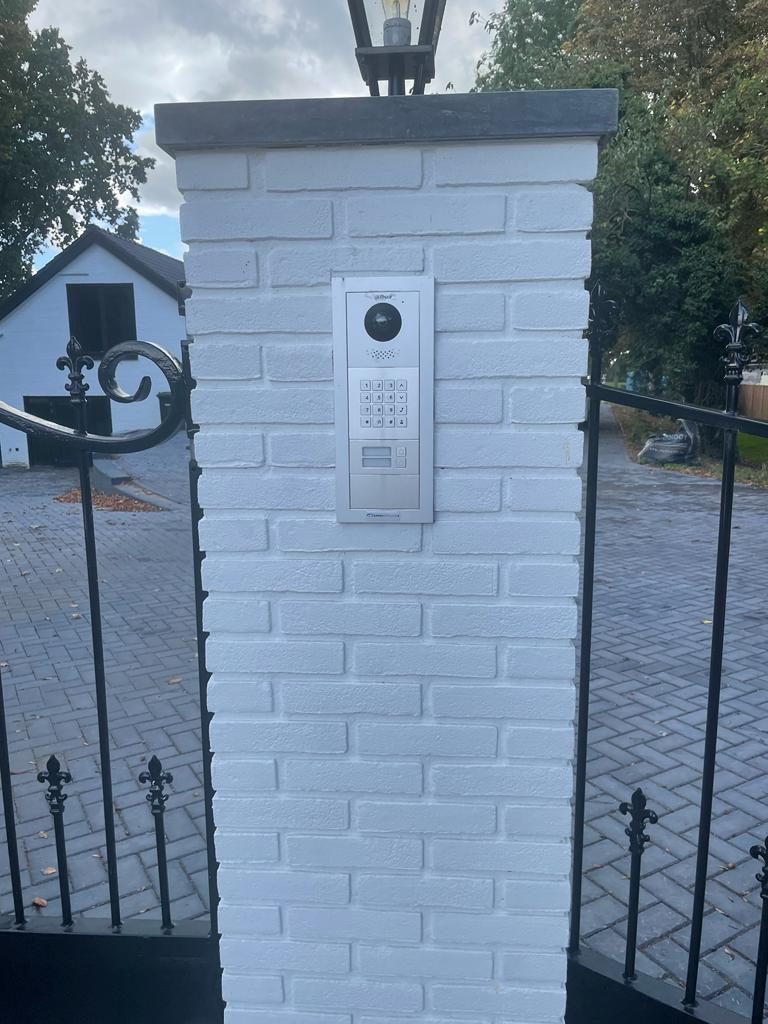 Intercom met camera en codeslot, ingebouwd in een witte poortpijler