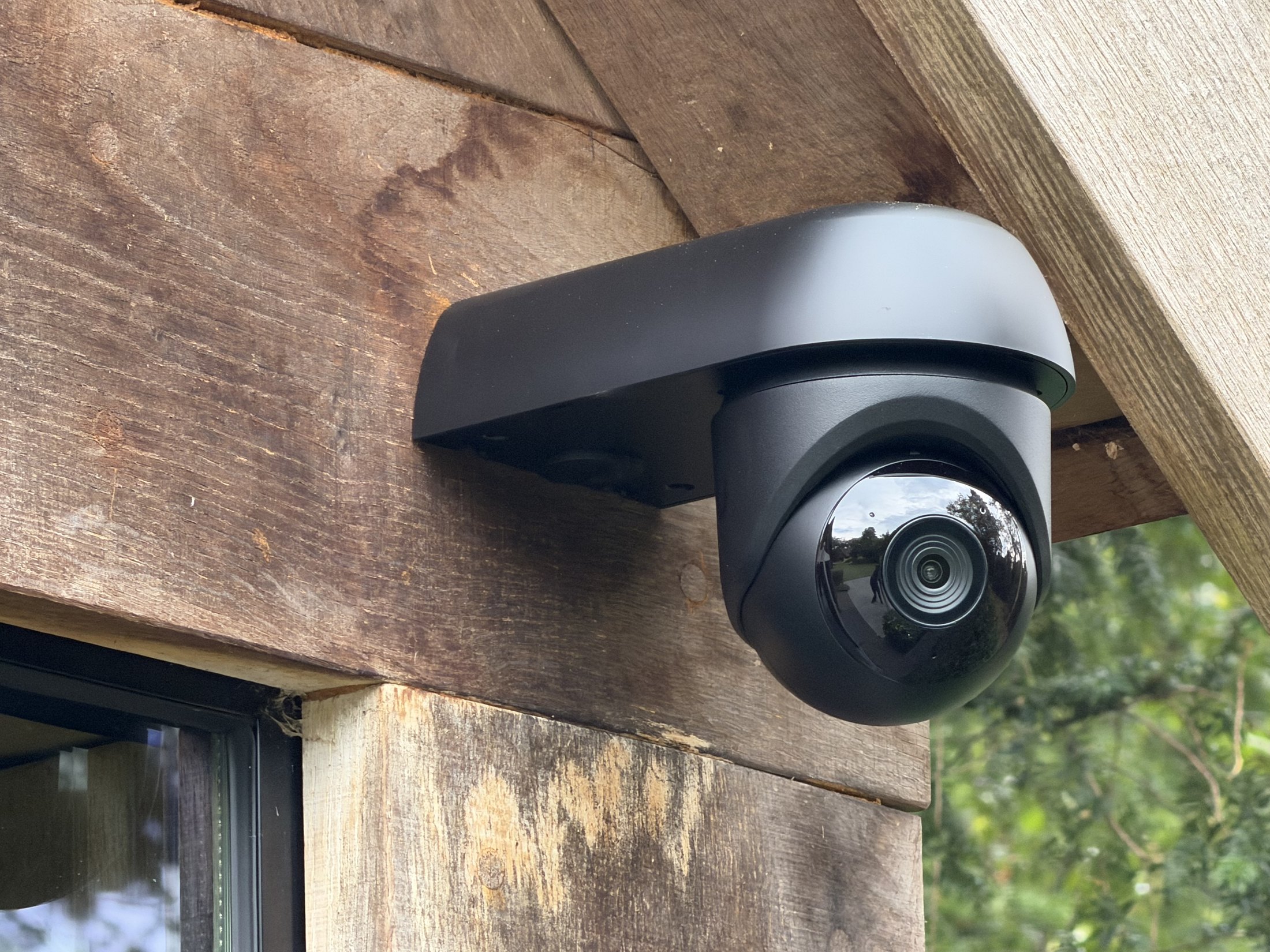 Zwarte draaibare camera met zonnekap onder een verweerde eiken balk