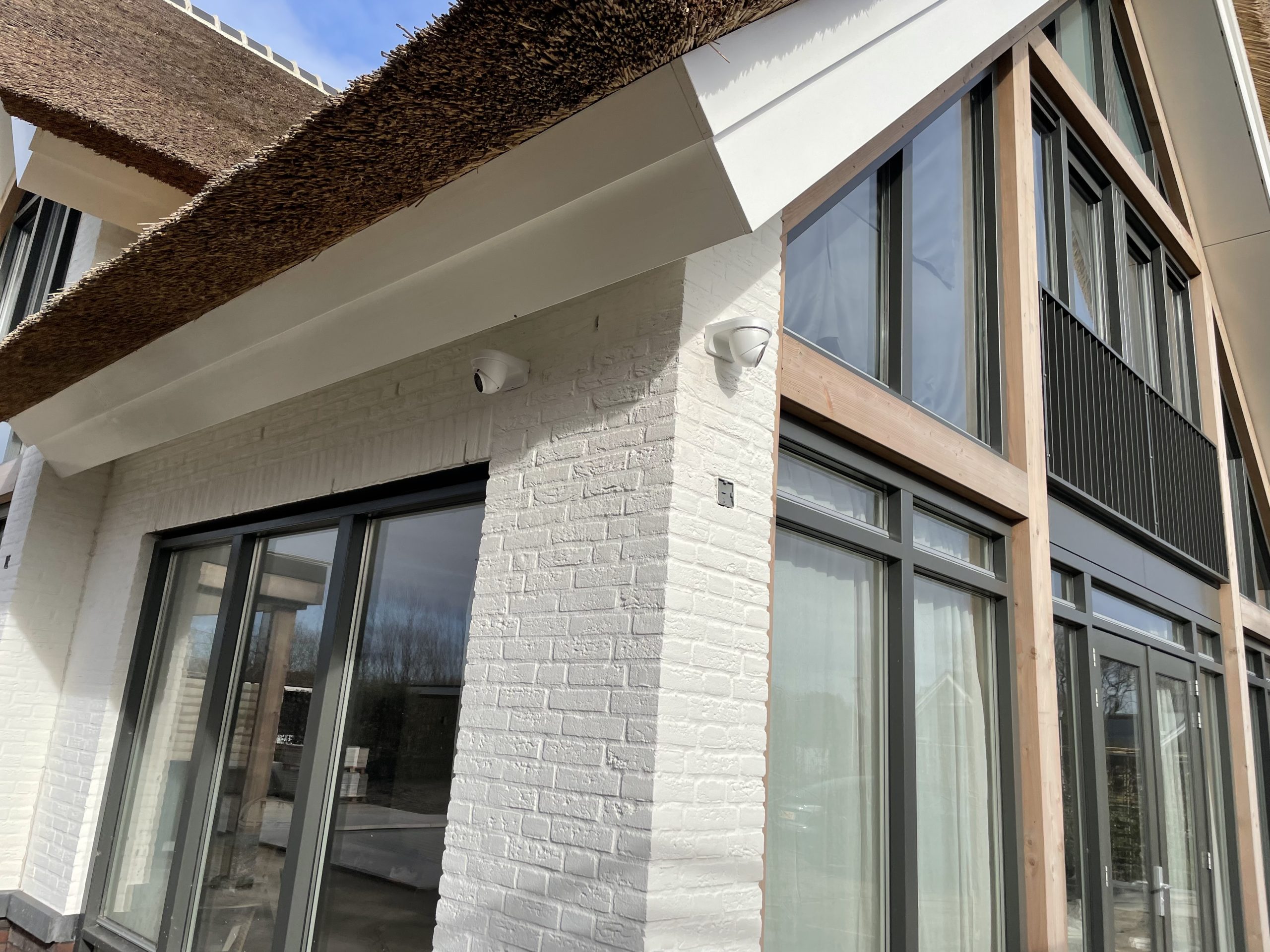 Witte turretcamera onder de boeideel van een rietgedekte villa met wit geschilderde gevelsteen