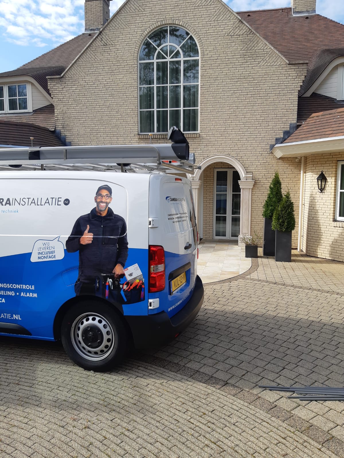 Onze servicebus op de klinkeroprit van een klassiek landhuis met rondboogvenster
