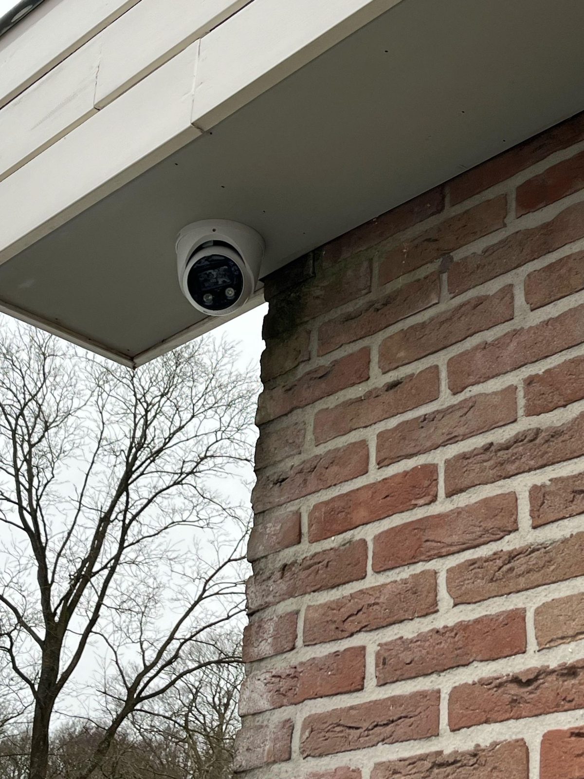 Witte camera strak tegen het boeideel van een woonhuis gemonteerd
