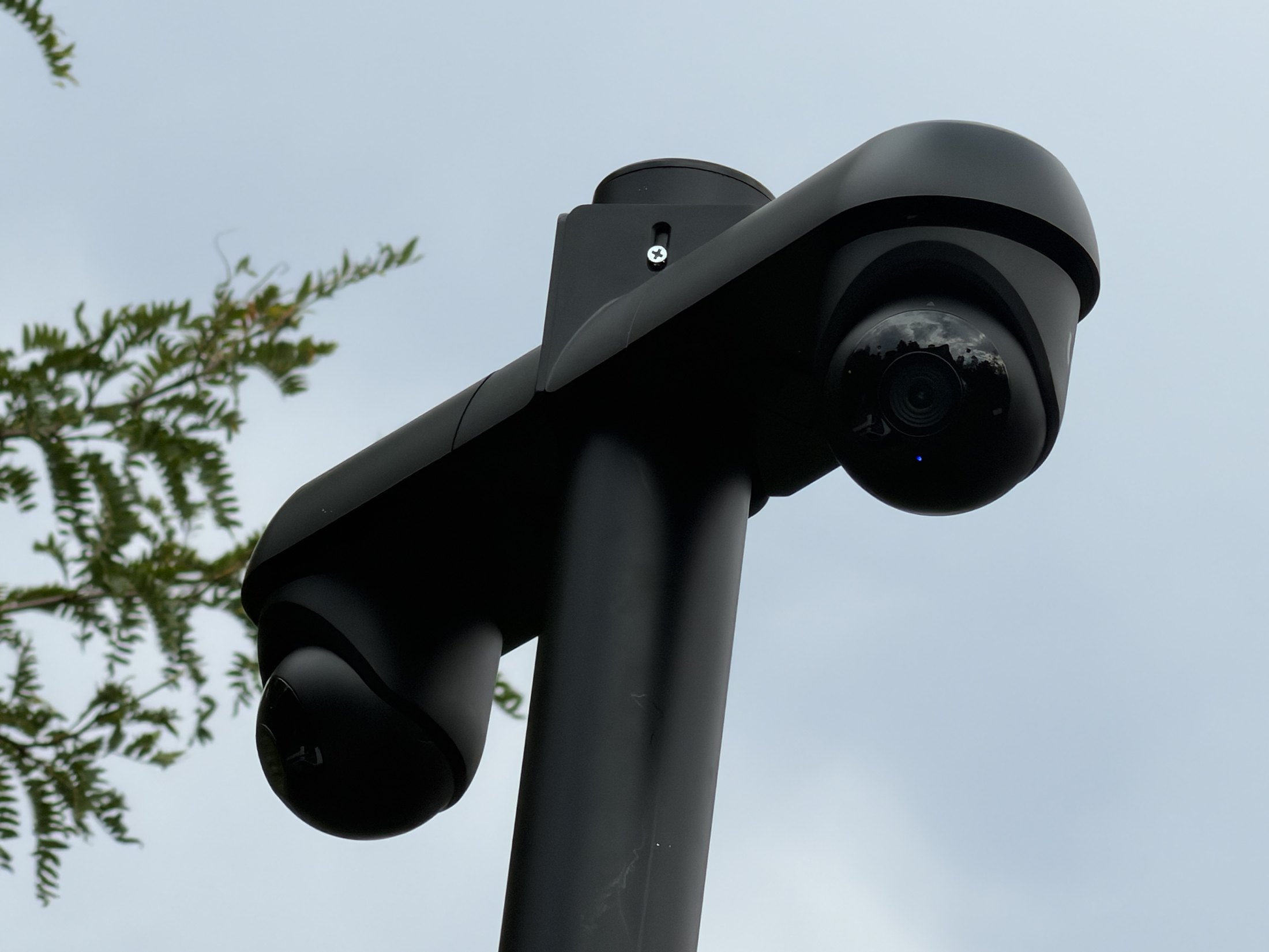 Twee zwarte draaibare camera's aan een arm, van dichtbij tegen de lucht
