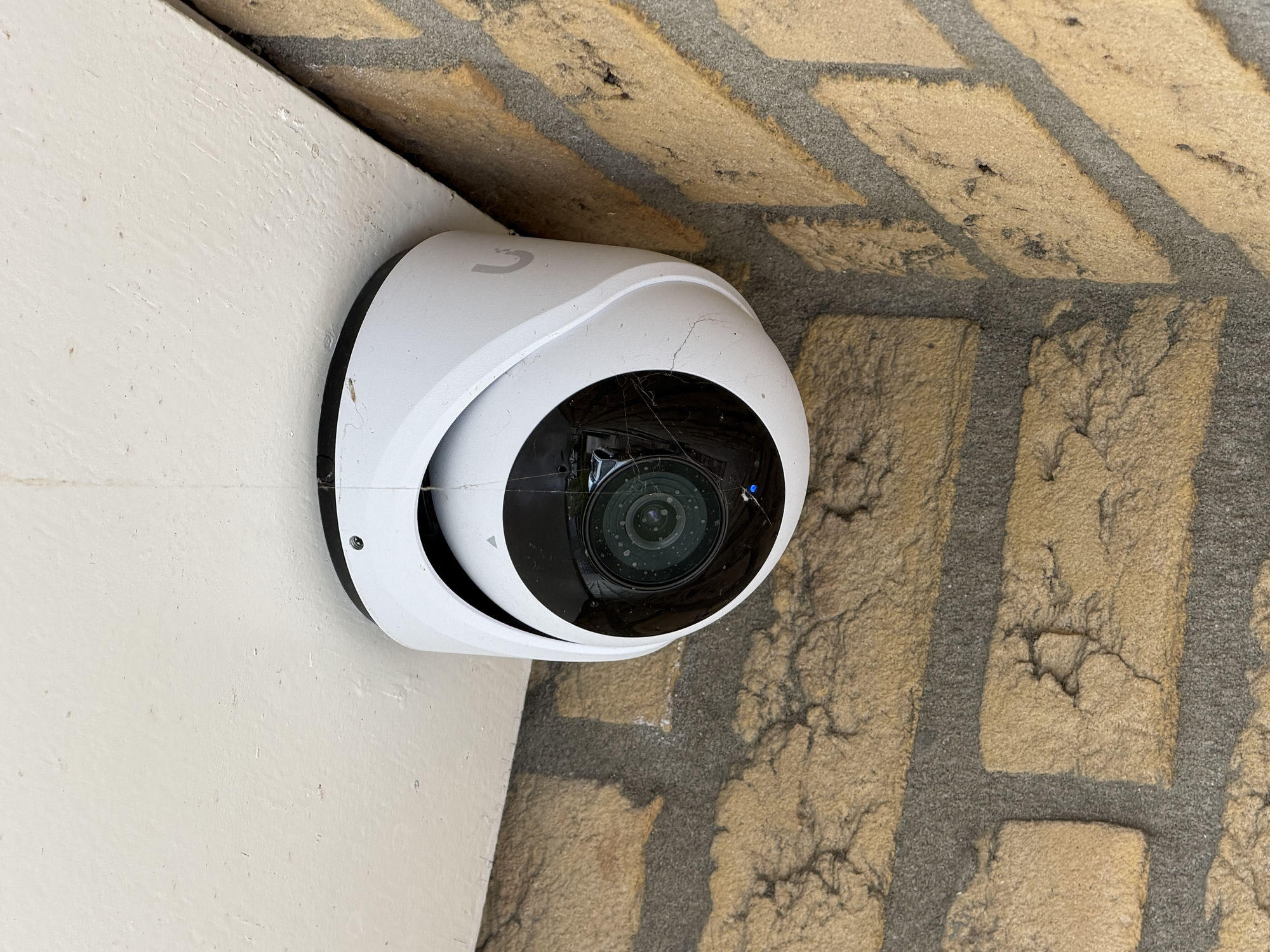 Witte turretcamera weggewerkt onder het boeideel op de hoek van een gele gevel