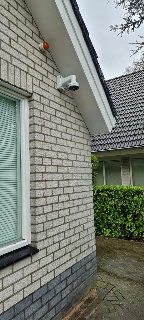 Witte camera hoog op de hoek van een lichte gevel met zicht langs het zijpad
