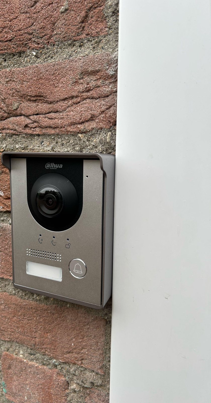 Intercom met camera bij de voordeur, op een witte kozijnlijst