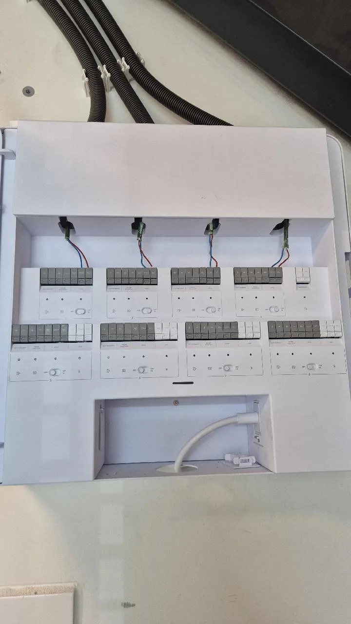 Geopende witte UniFi Access-hub met acht deuraansluitingen en kabels in zwarte buis van boven