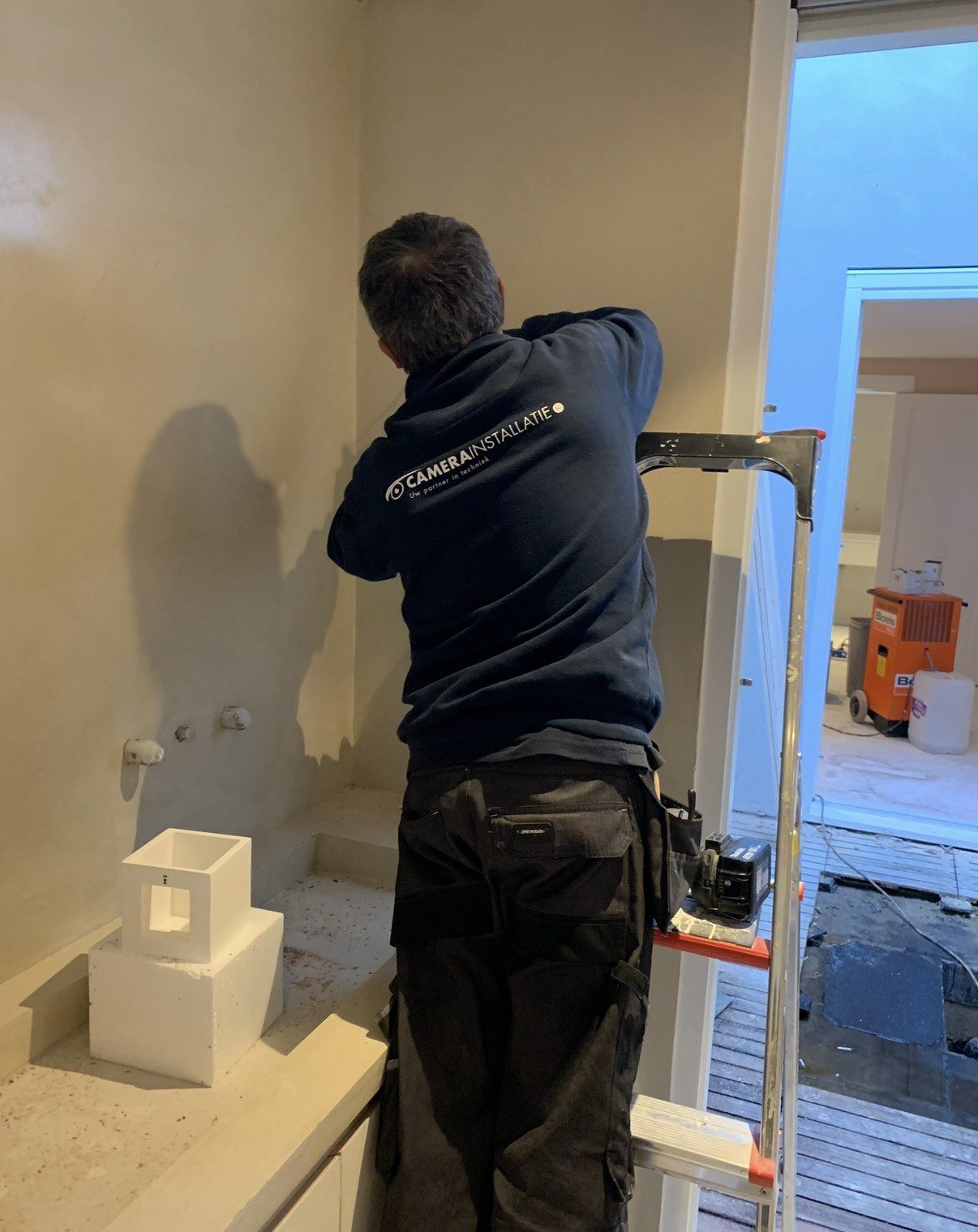 Monteur werkt aan aansluitingen in een wand voordat die dichtgaat
