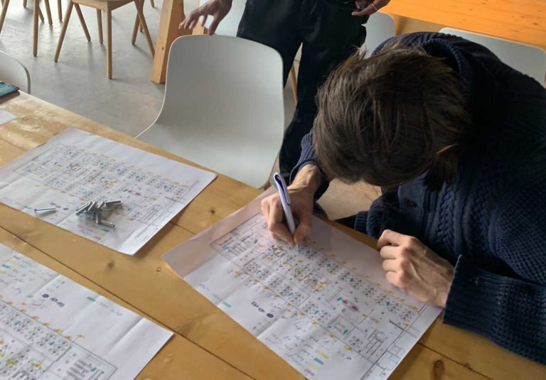 Iemand tekent met een pen op plattegronden van het schip, met de plek van elke zender