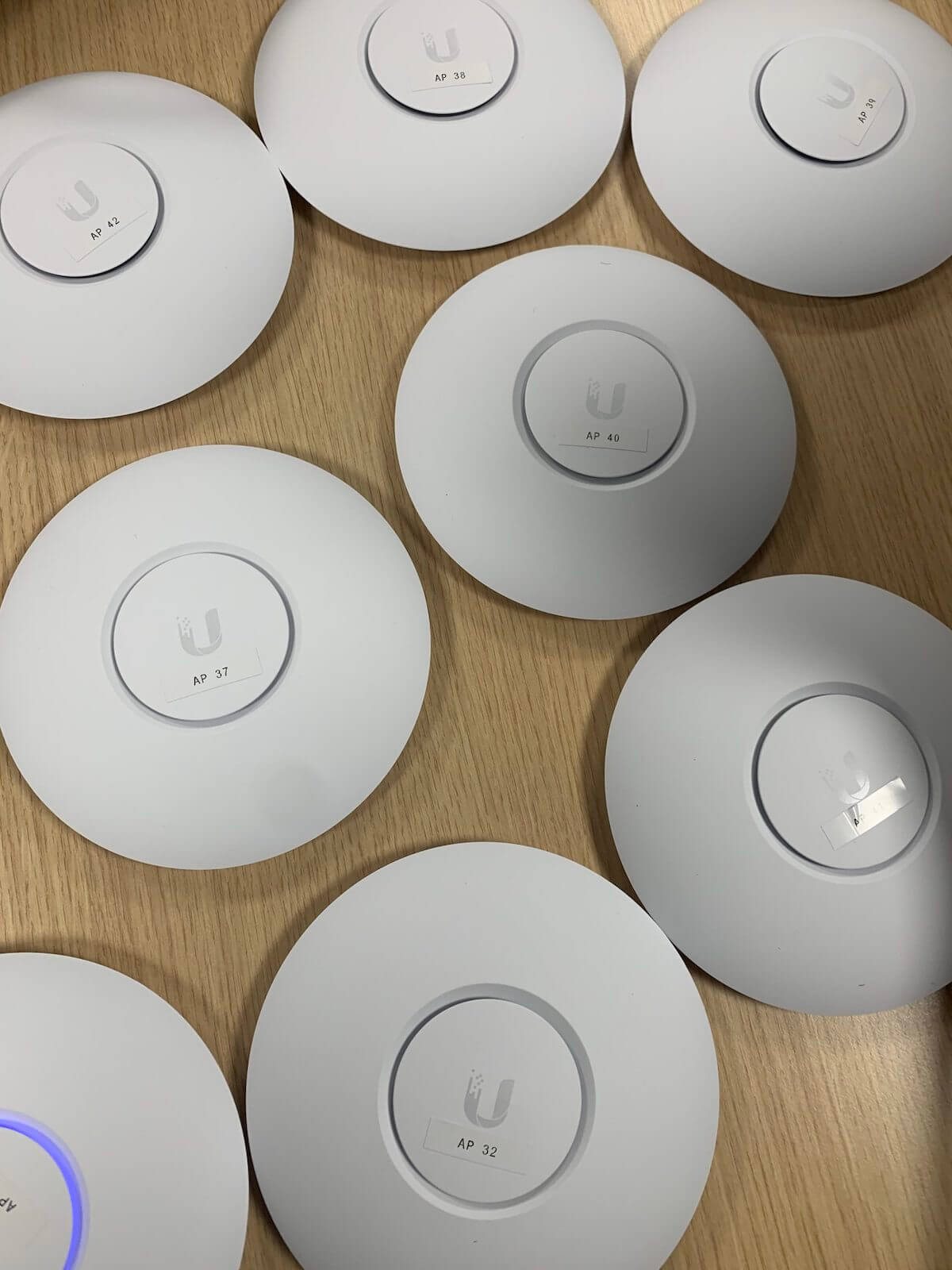 Een stapel witte wifizenders op tafel, elk met een nummer op de achterkant