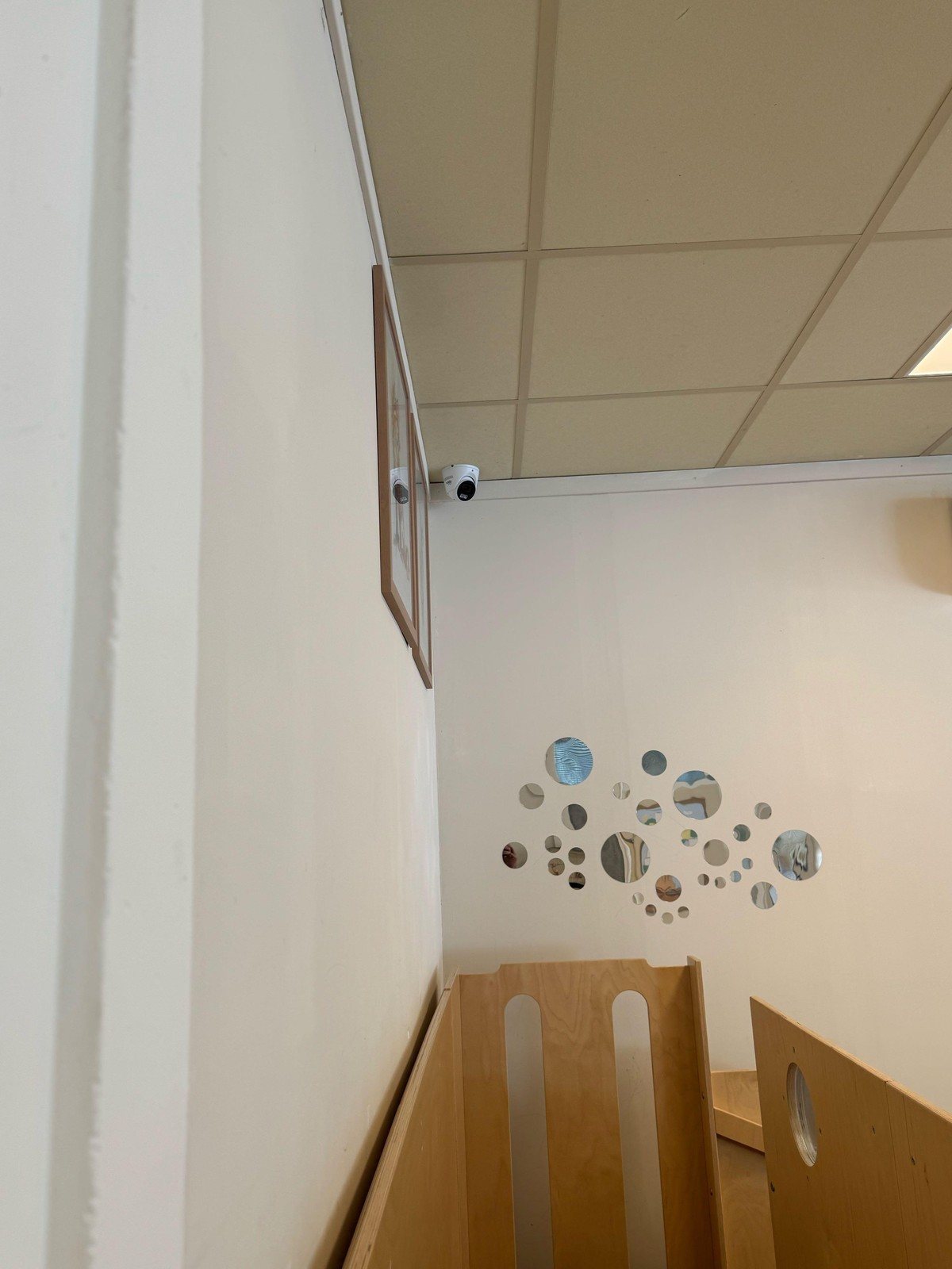 Camera boven een trap in een lichte gang, met een wandversiering
