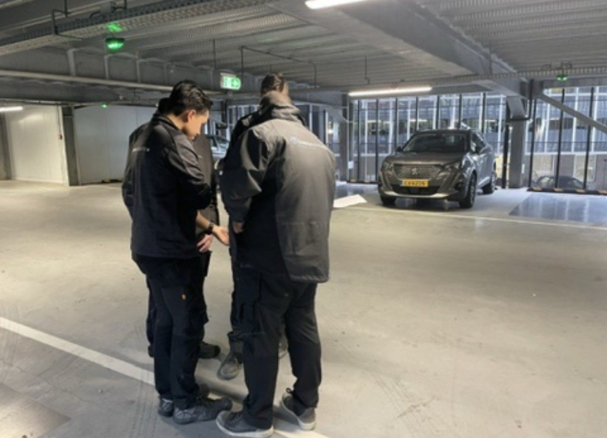 Monteurs overleggen op de parkeervloer aan de hand van het kabelschema