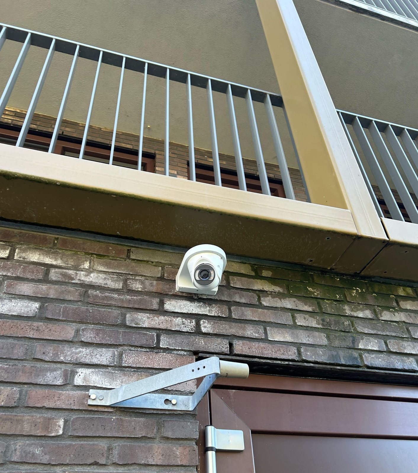 Witte camera onder een galerij van een appartementencomplex